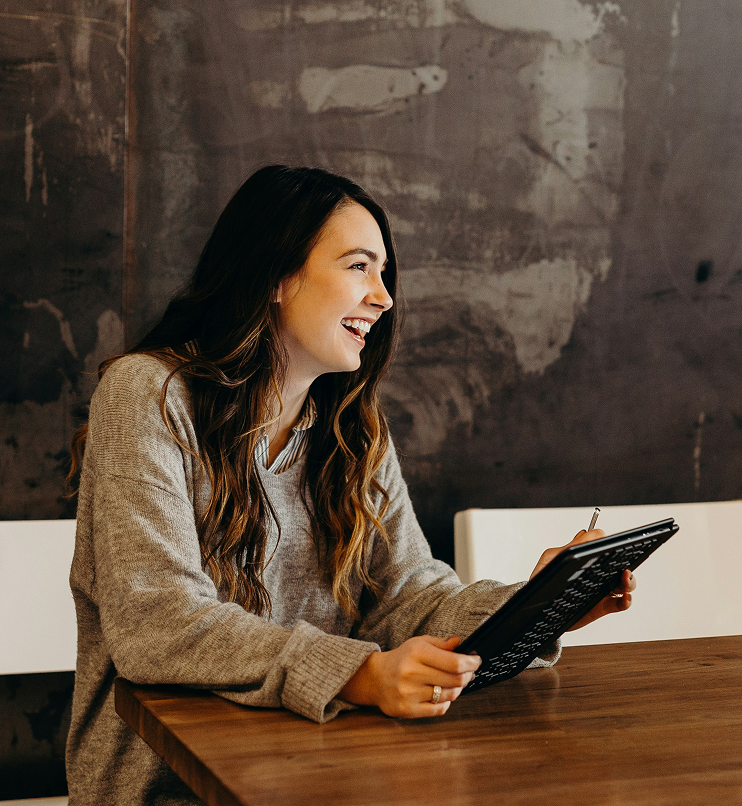 A smiling woman working on her tablet at a table.